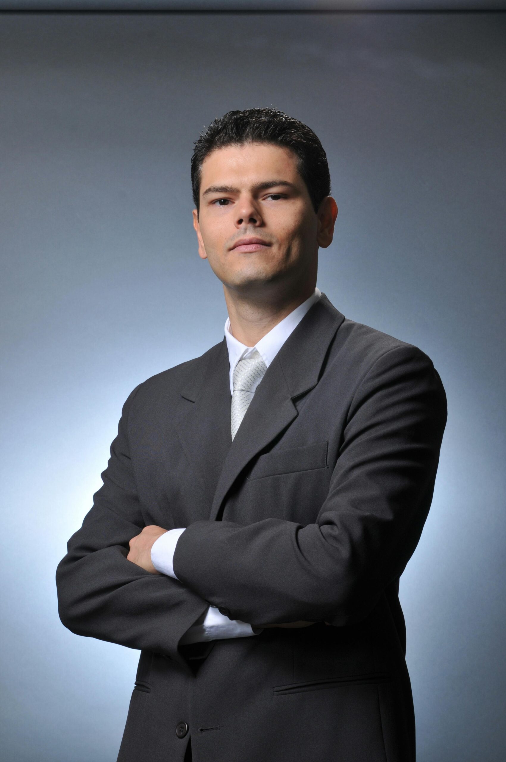 Confident businessman wearing a gray suit with crossed arms. Professional formal portrait.